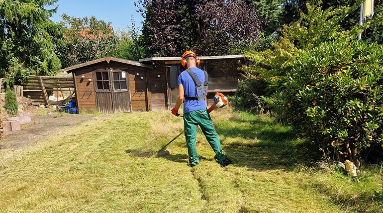 Mitarbeiter von Haus- & Gartenservice Bremen mäht Rasen mit dem Freischneider